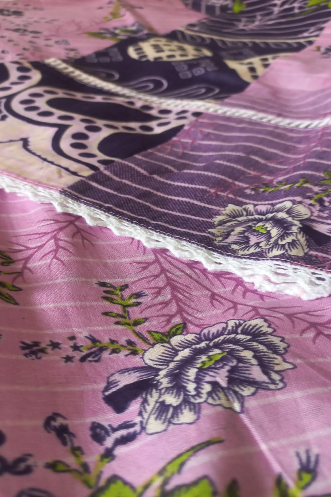Amira Stitched close-up of a fabric with purple floral patterns on a pink background