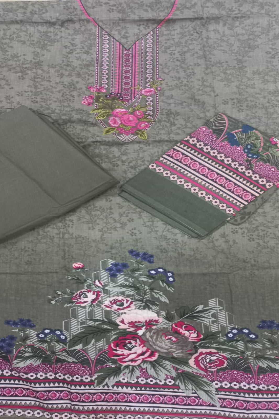 Green fabric with floral and geometric patterns, including pink roses and blue flowers.