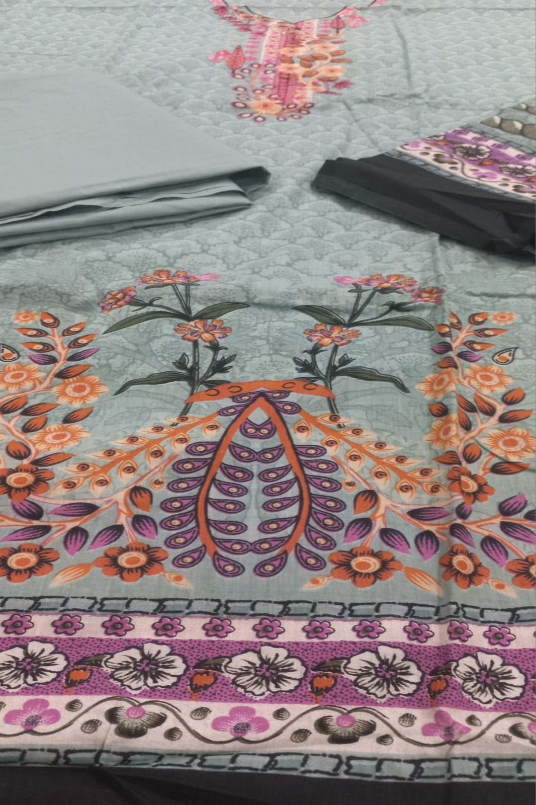 Decorative tablecloth with floral and paisley patterns on a checkered tablecloth.