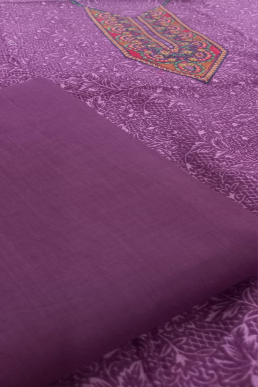 Burgundy fabric with intricate patterns and a colorful border