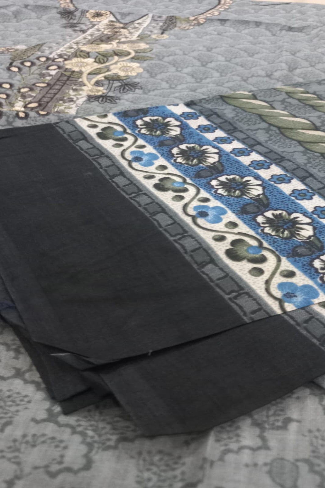 Black fabric with a floral border on a textured surface